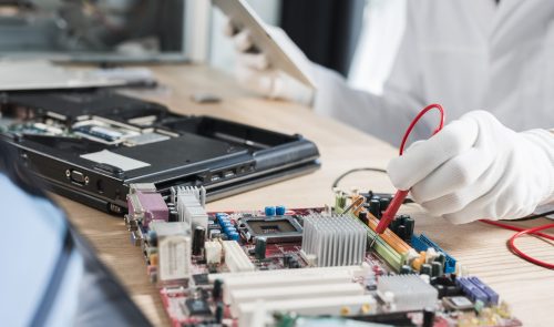 male-technician-examining-mother-board-with-digital-multimeter